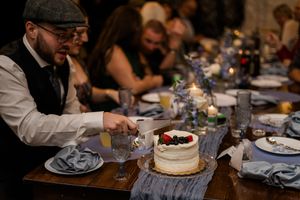 People gather around a rustic wooden table enjoying desserts and conversation at a casual dinner party.