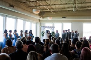 Indoor wedding ceremony with large windows and industrial ceiling features.