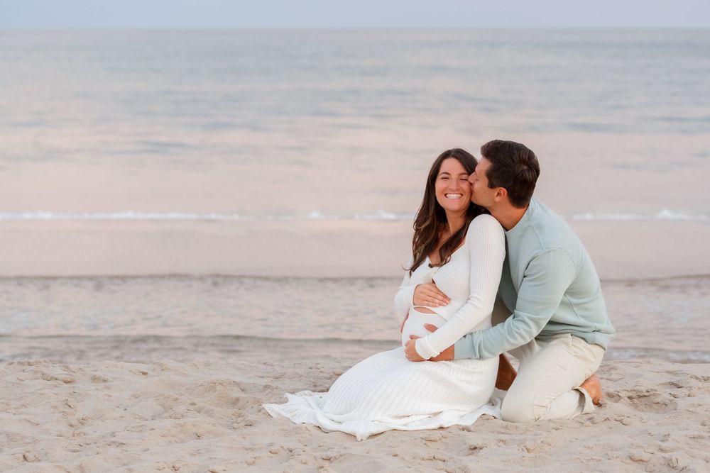 A couple shares romantic moments together on a sandy beach during sunset.