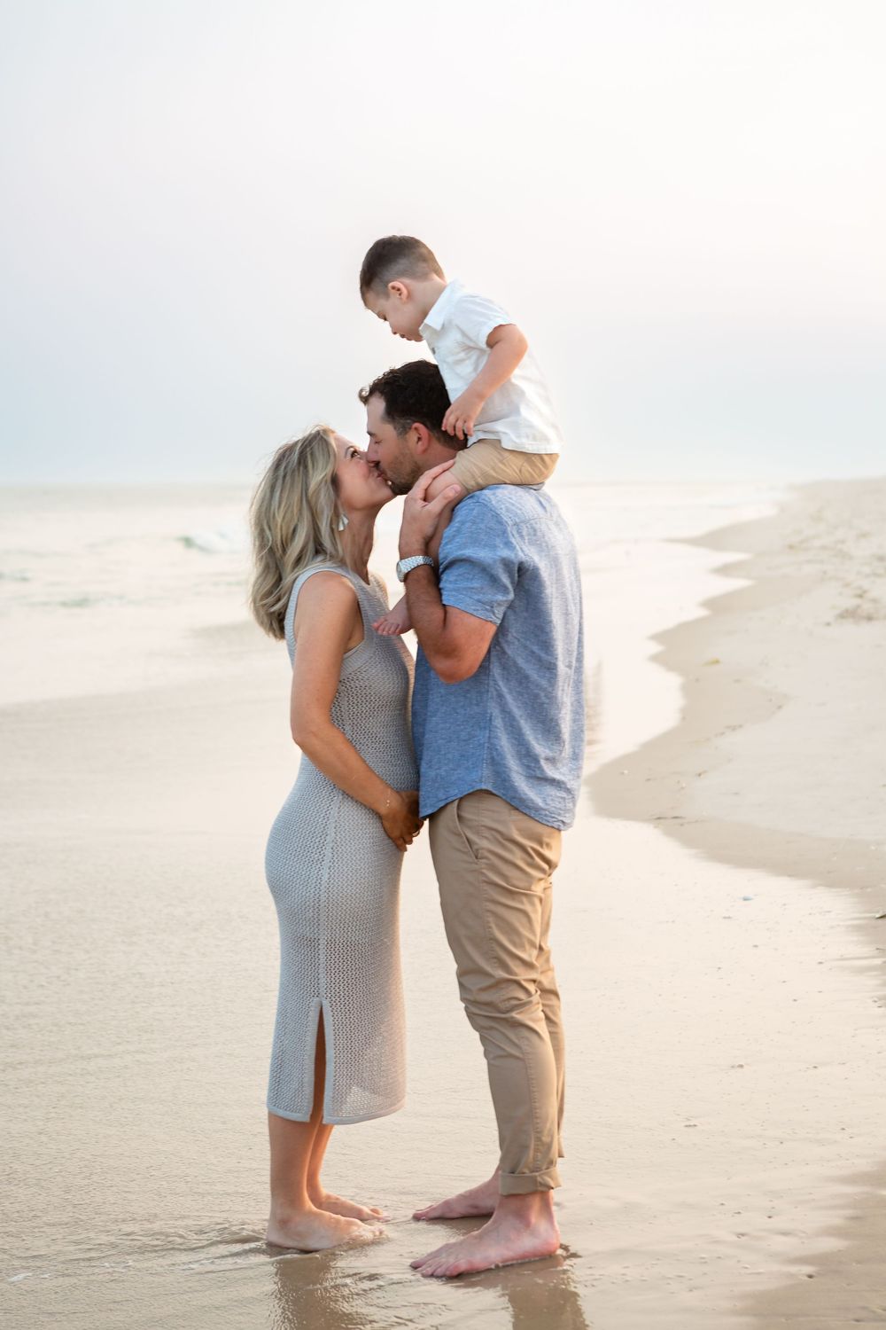 A couple embraces romantically on a sandy beach during sunset, creating a dreamy seaside moment.