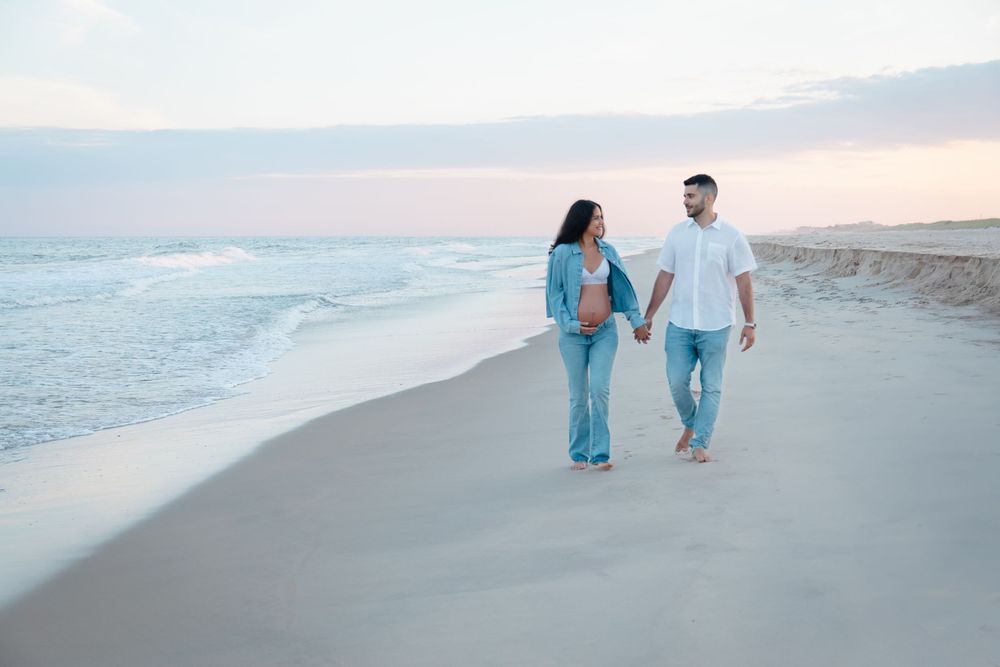 Romantic beach photoshoot with couple sitting on sandy shore at dusk.