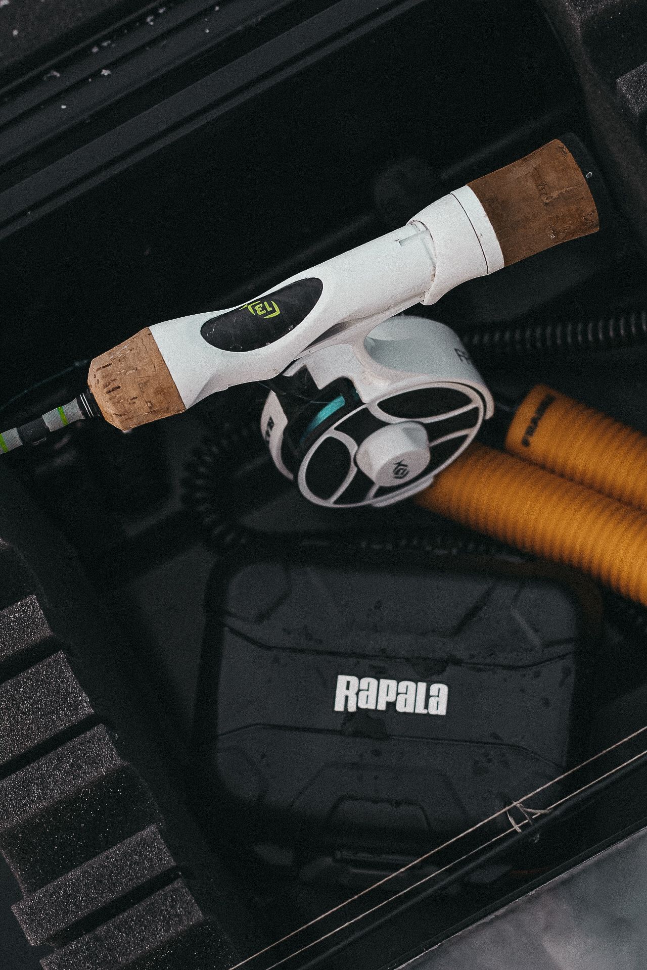 Rapala fishing equipment and rods stored in a dark vehicle compartment.