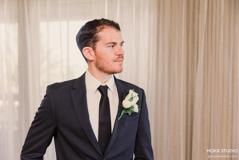 A group of groomsmen in dark suits and ties stand together at a formal wedding event.