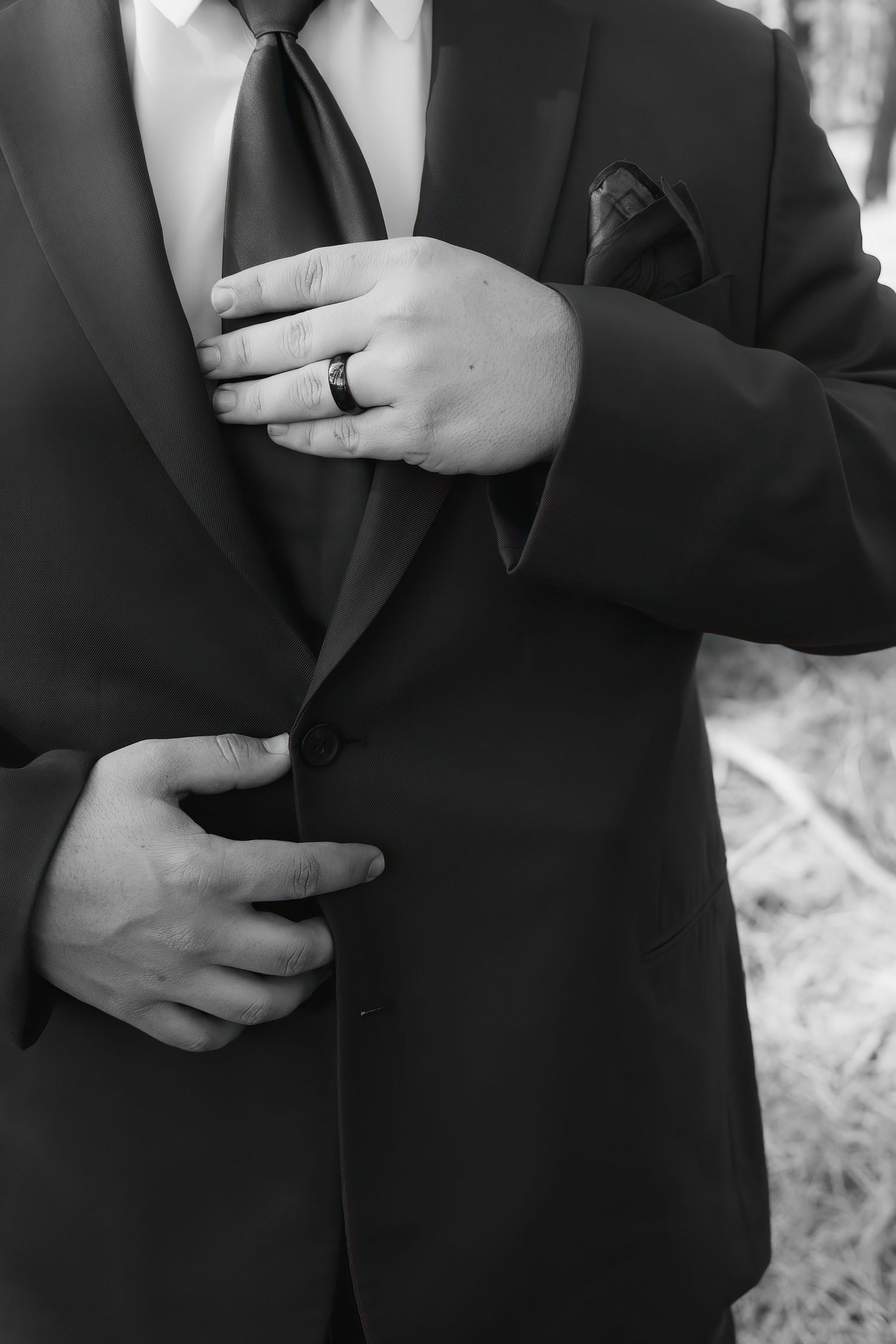 Close-up of a groom's hands adjusting his black suit jacket and wedding ring at a Eastern Oregon Wedding.