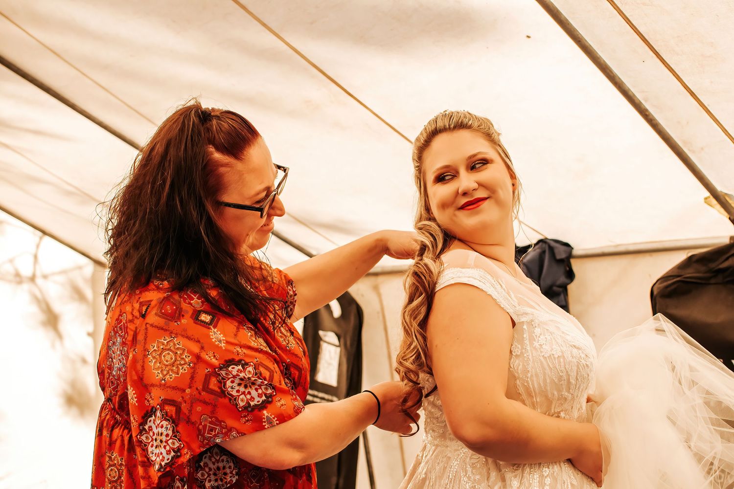 Behind-the-scenes moment of final wedding dress preparations inside a tent with mother of the bride and bride in Eastern Oregon.