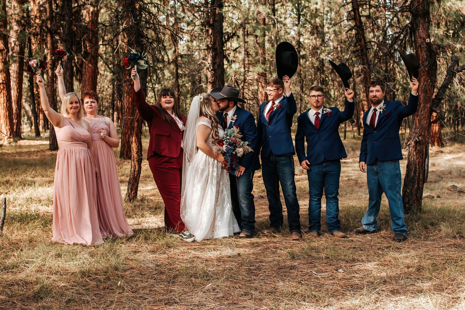 Wedding party posing in coordinated blue and pink attire against a forest backdrop in Oregon.