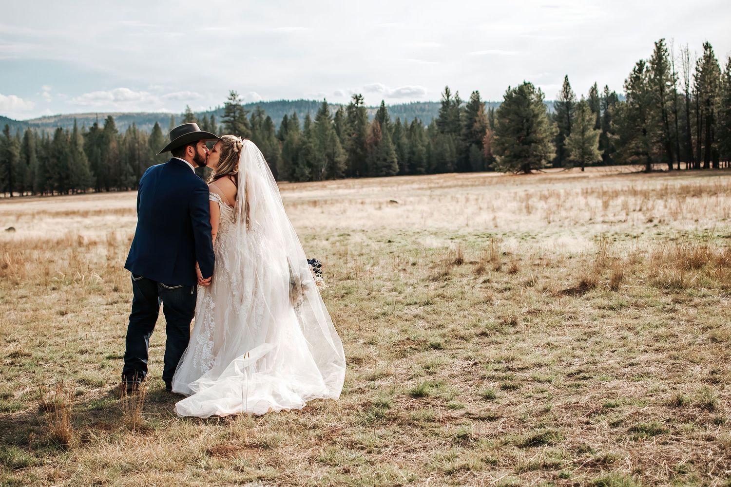Romantic moment between newlyweds in an open field with mountain views in Eastern Oregon.