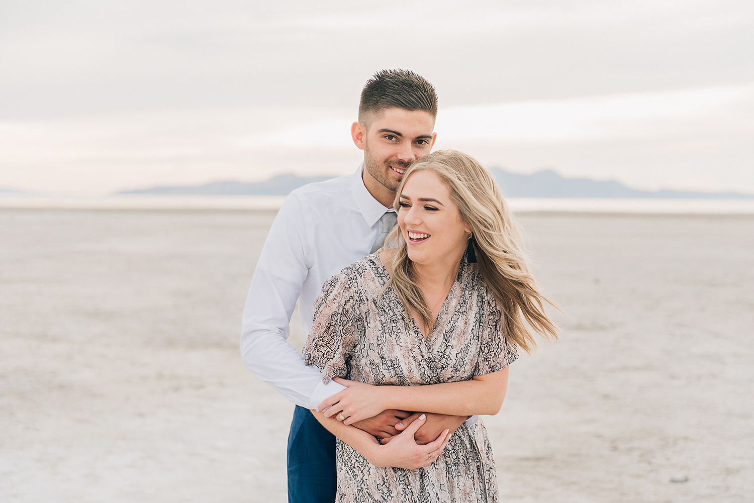 Joyful moment captured of couple laughing together on scenic salt flats.