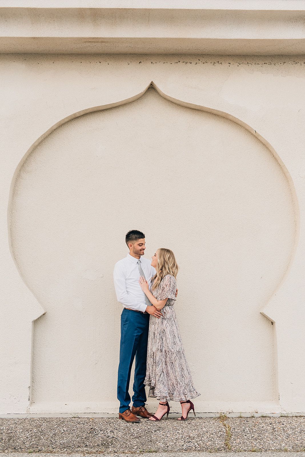 Stylish couple posing in elegant archway for engagement photos.