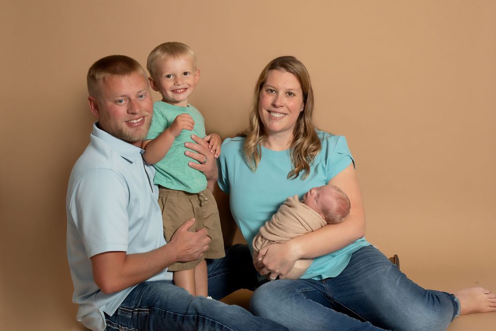 Family portrait with matching outfits against brown backdrop during studio photo session.