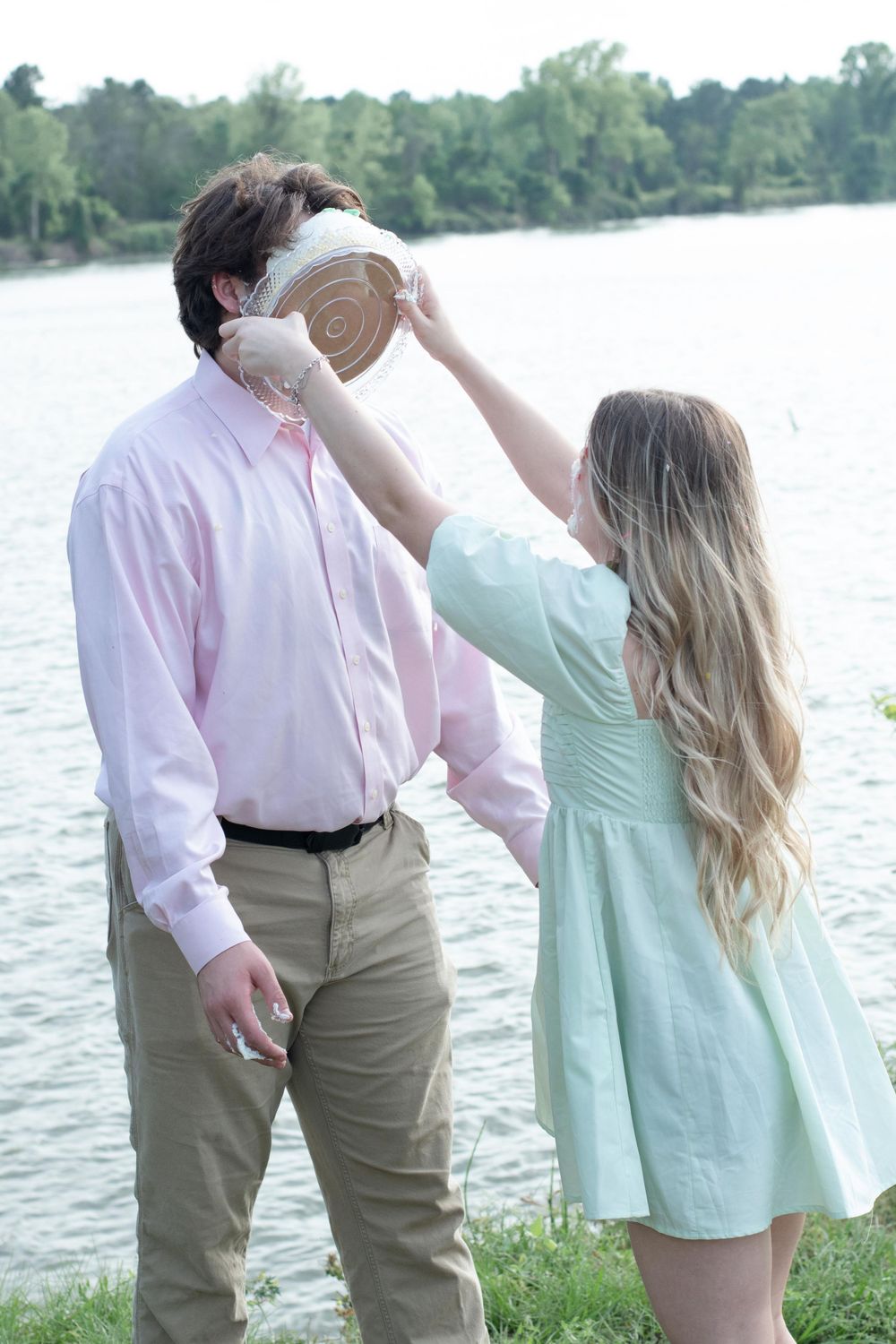 A playful moment by the lake with someone getting cake smeared on their face.