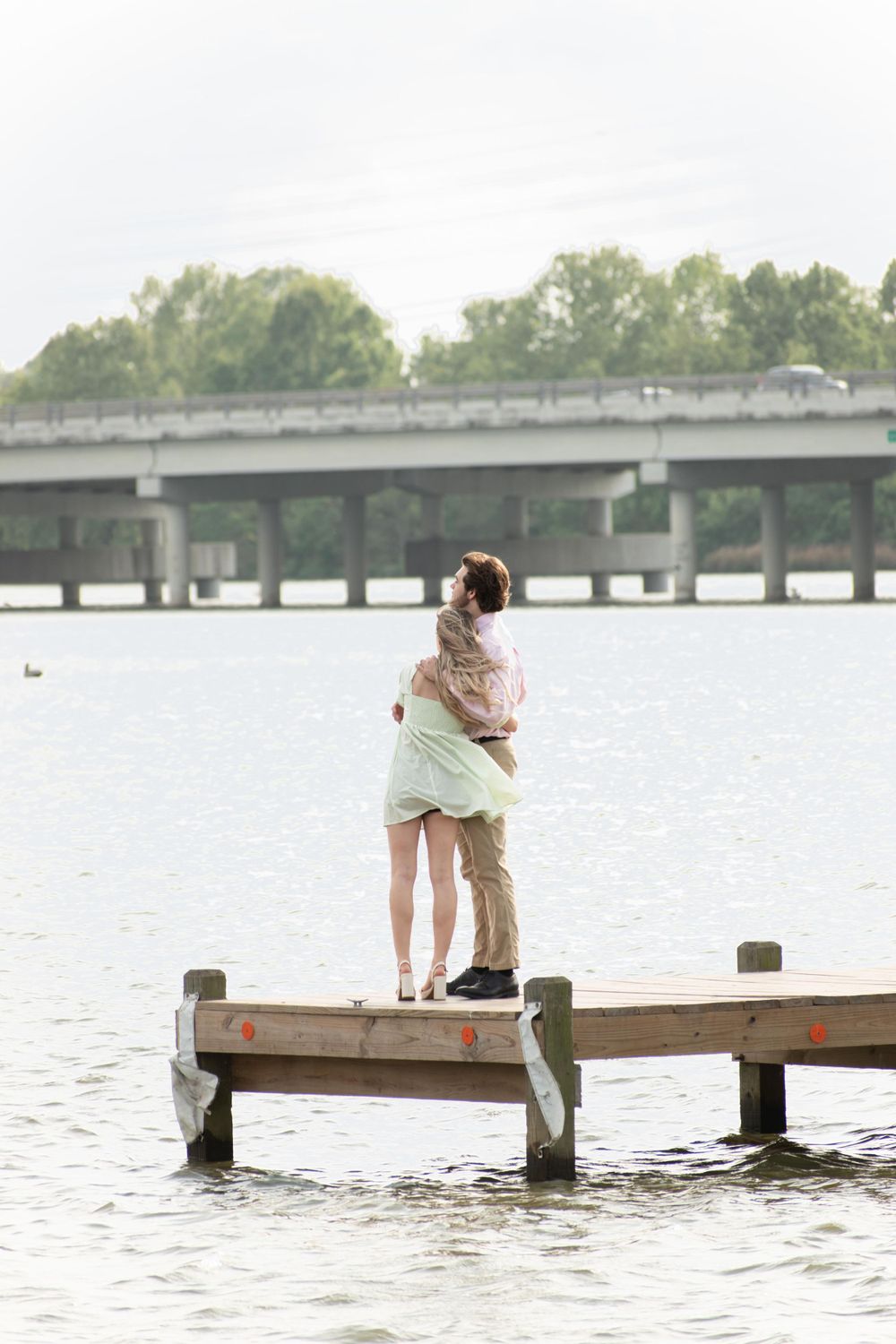 A romantic embrace on a wooden dock overlooking a serene lake.