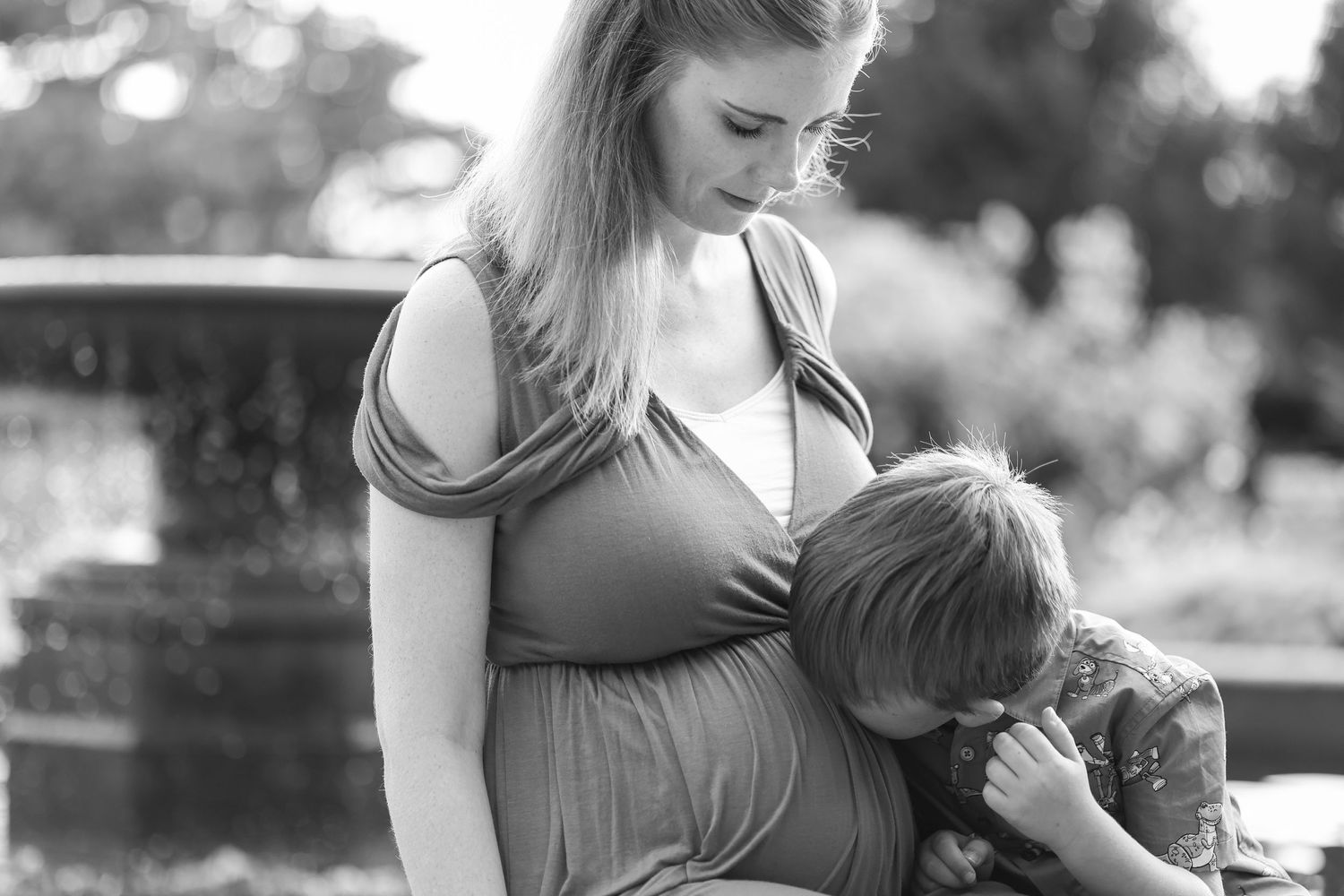 Black and white portrait of a tender parenting moment on a park bench.