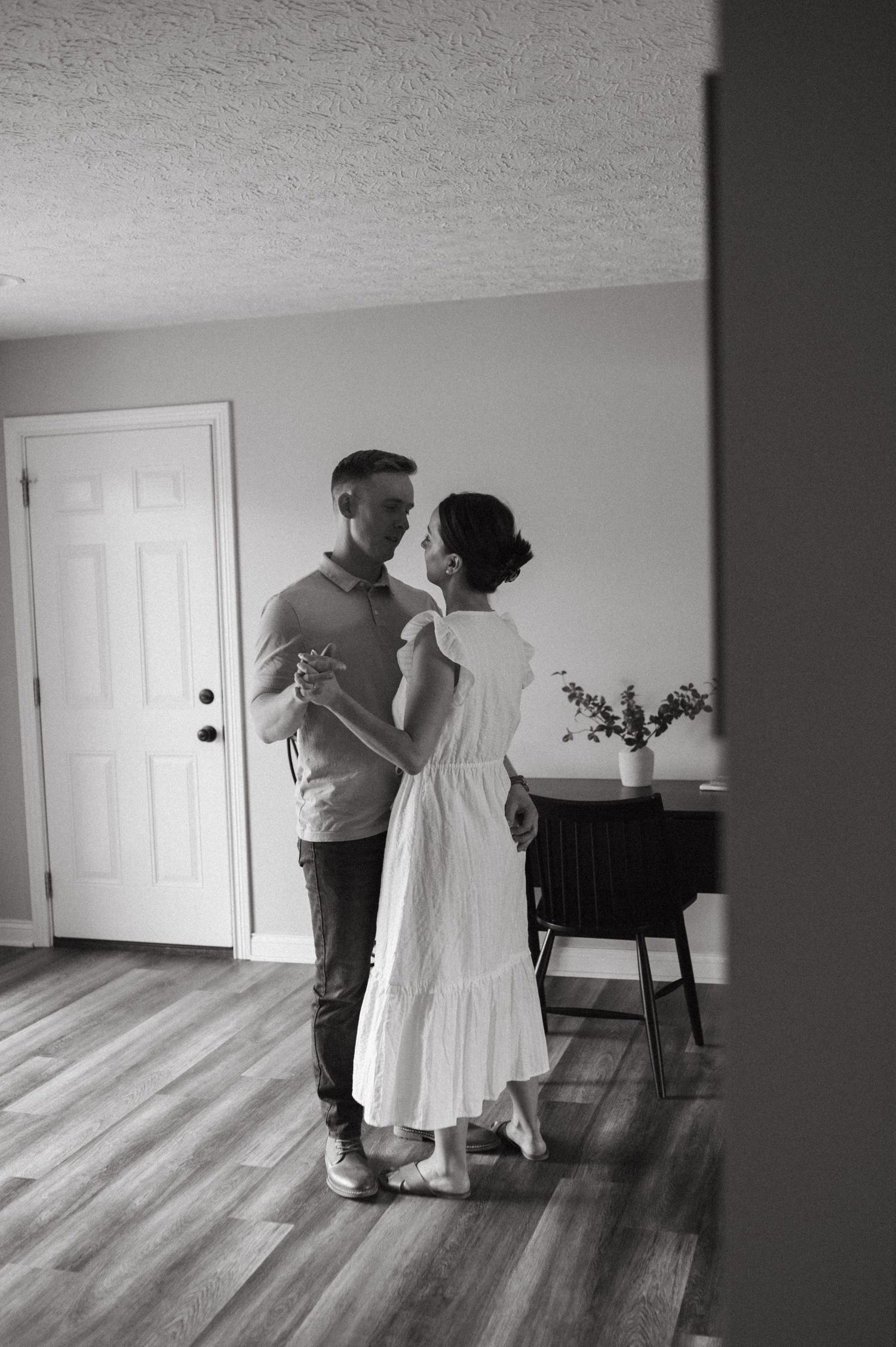 A black and white photo captures a couple dancing in their minimalist living room.