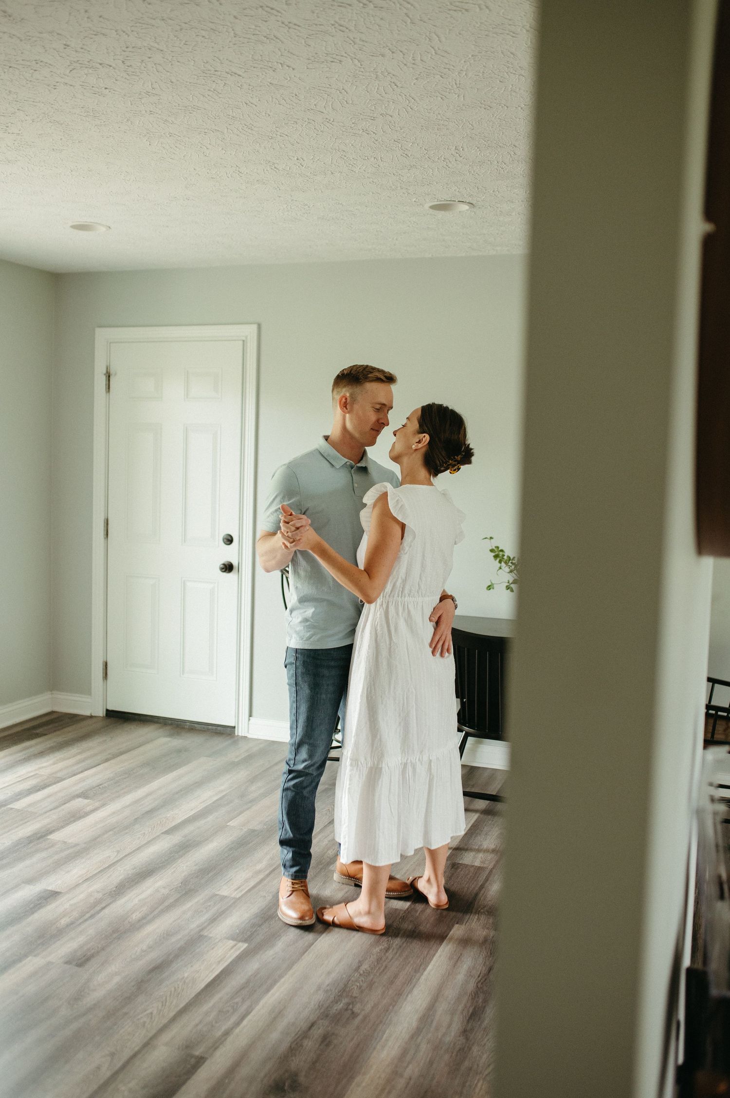 A couple dances together in their modern living room with hardwood floors.