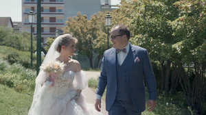 Outdoor wedding celebration with trees and buildings in background.