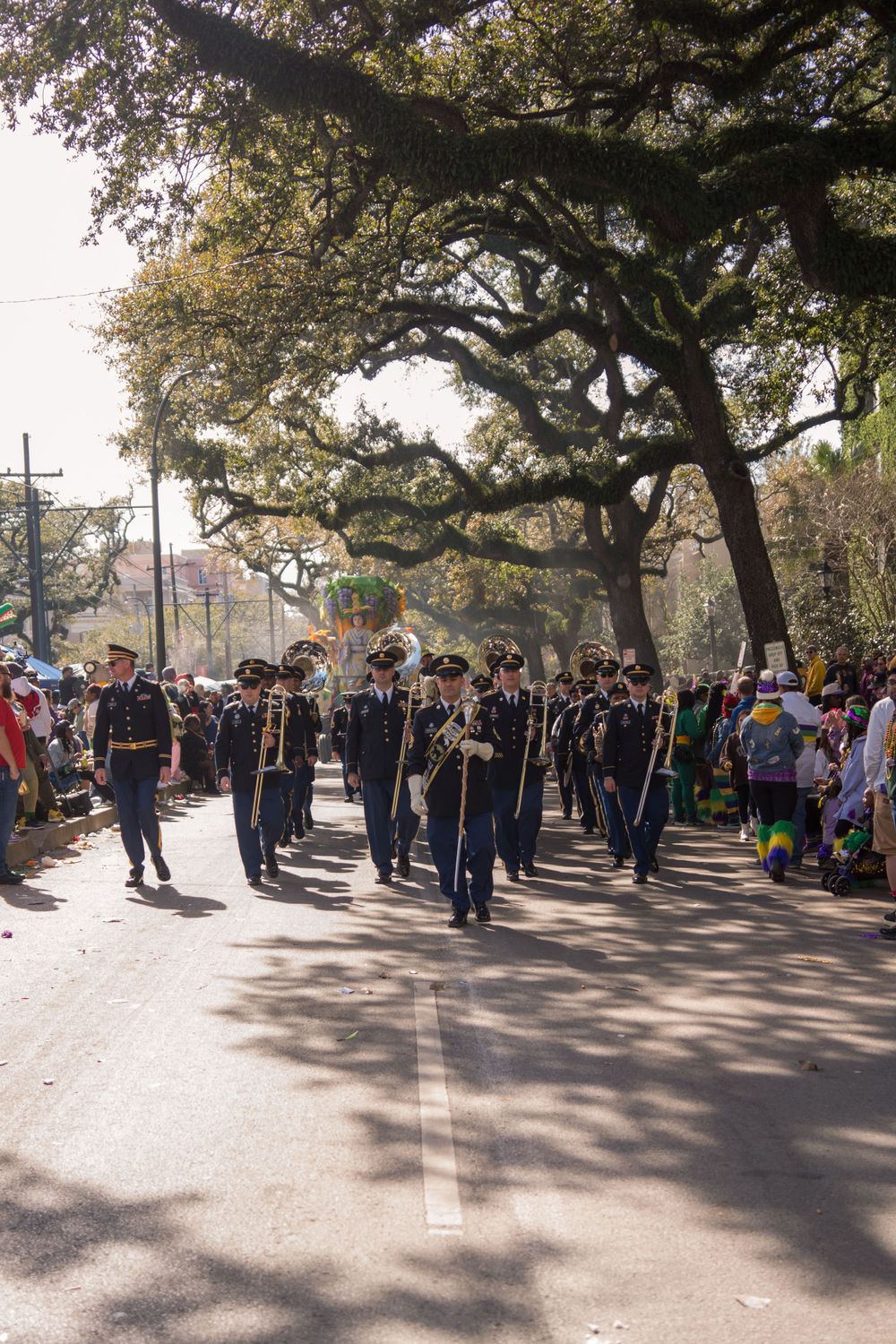 Large crowd gathered under oak trees at an outdoor event on a sunny day.