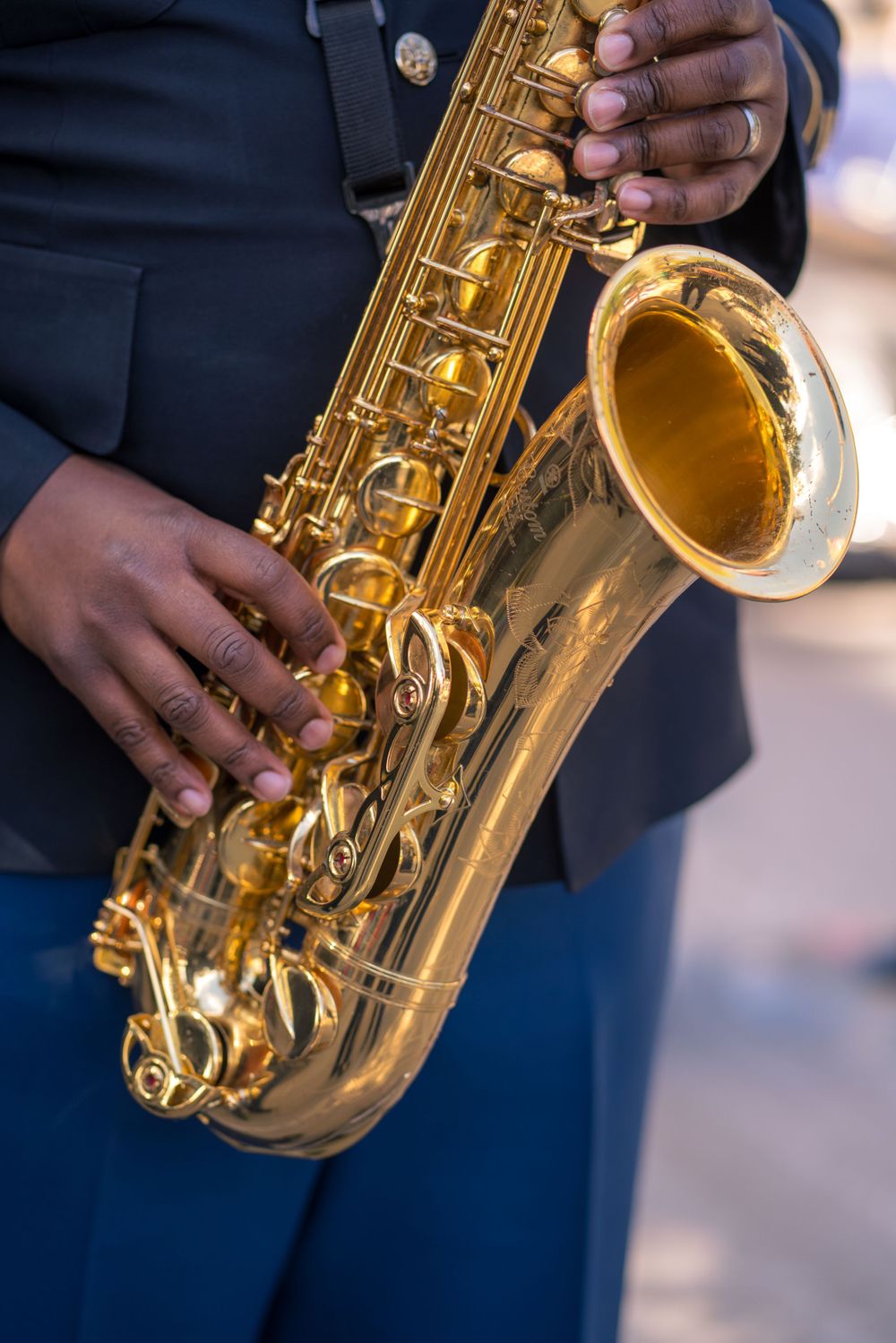 Close-up details of a shiny brass saxophone being played, showing the instrument's golden keys and mechanisms.