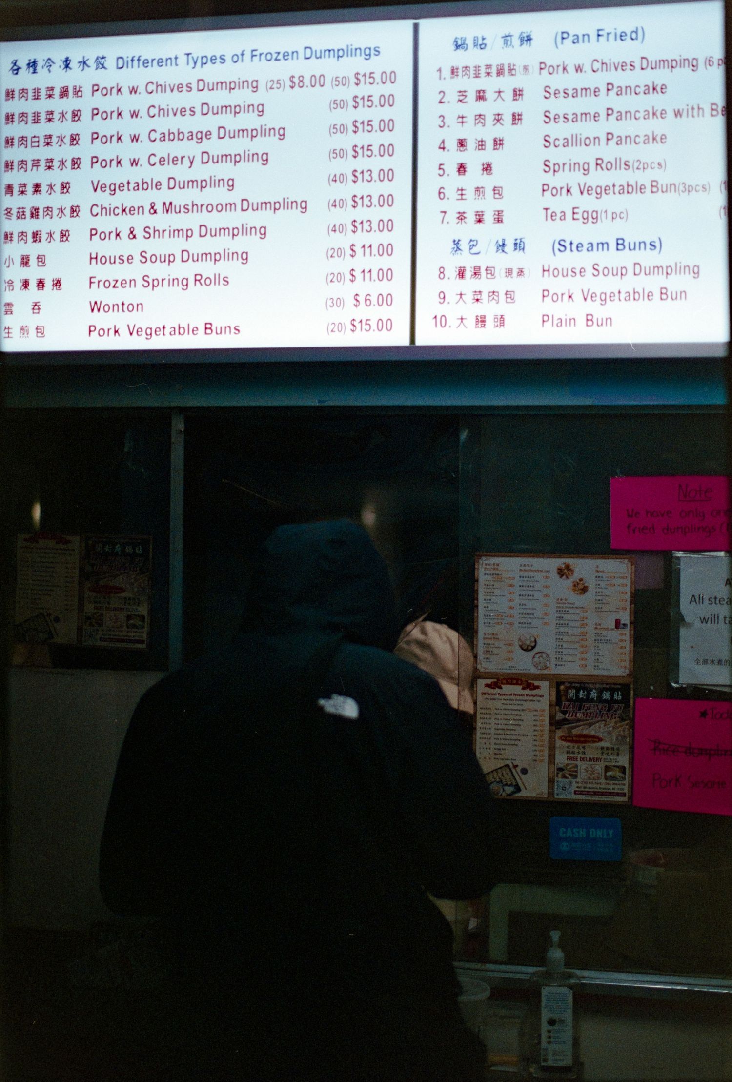 Chinese restaurant menu board displaying prices for various frozen dumplings and Asian dishes.