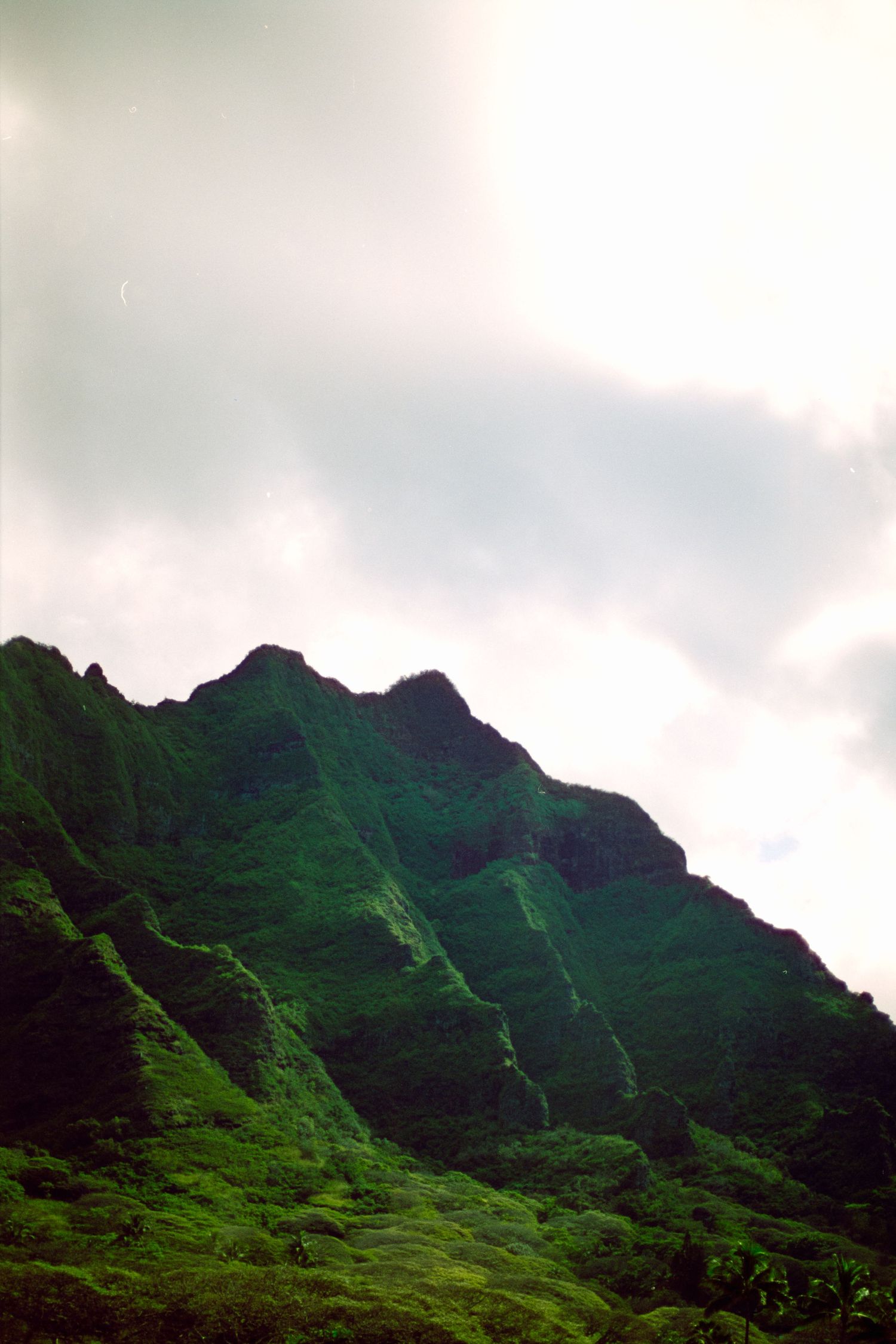 Lush green mountain ridges against cloudy sky in Hawaii.
