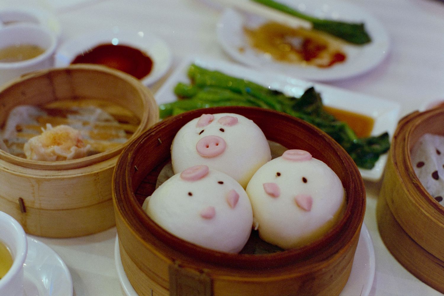 Cute steamed bao dumplings with pig faces served in bamboo steamers.