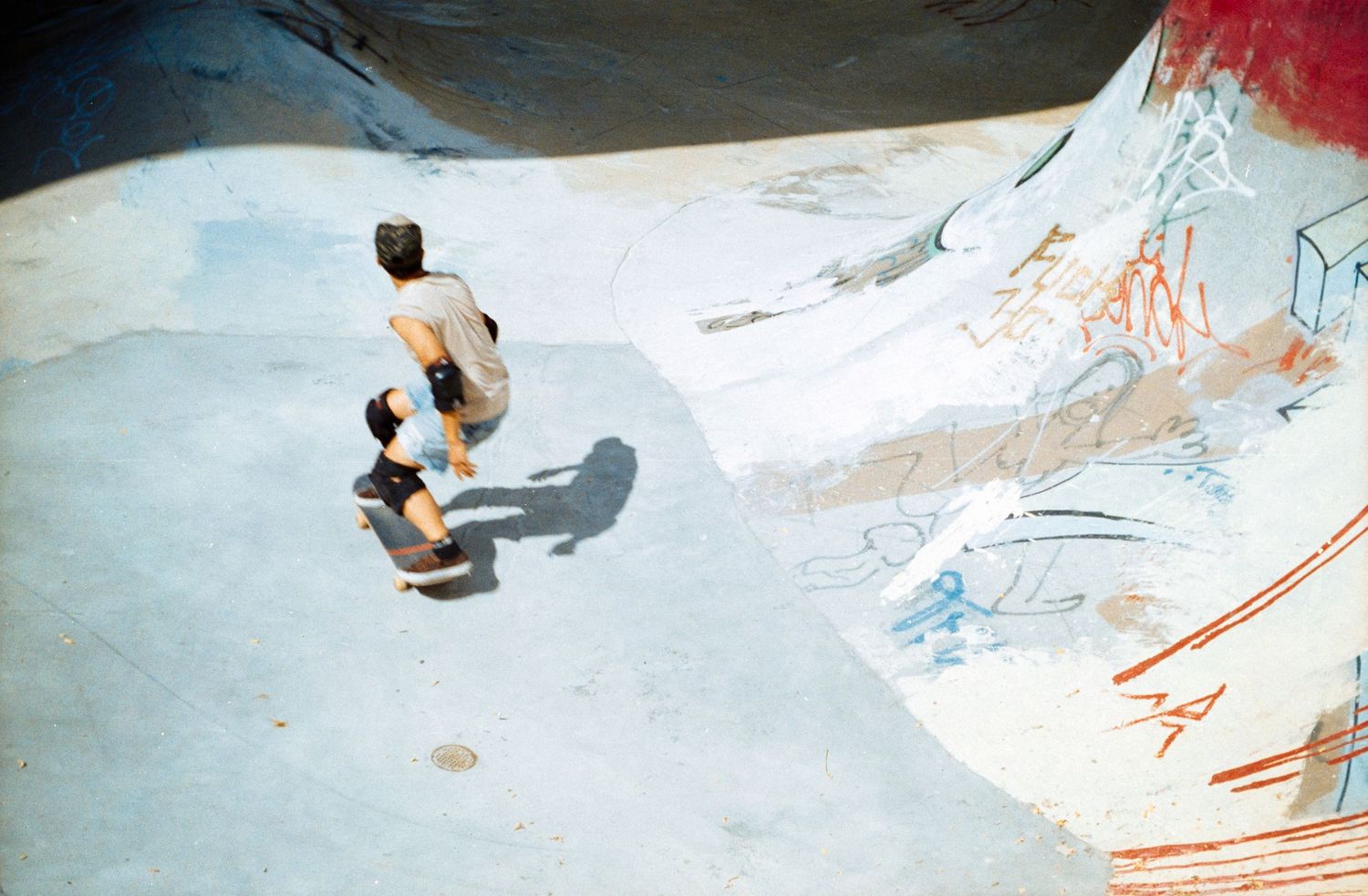 Skateboarders performing tricks in an empty concrete skate park bowl.