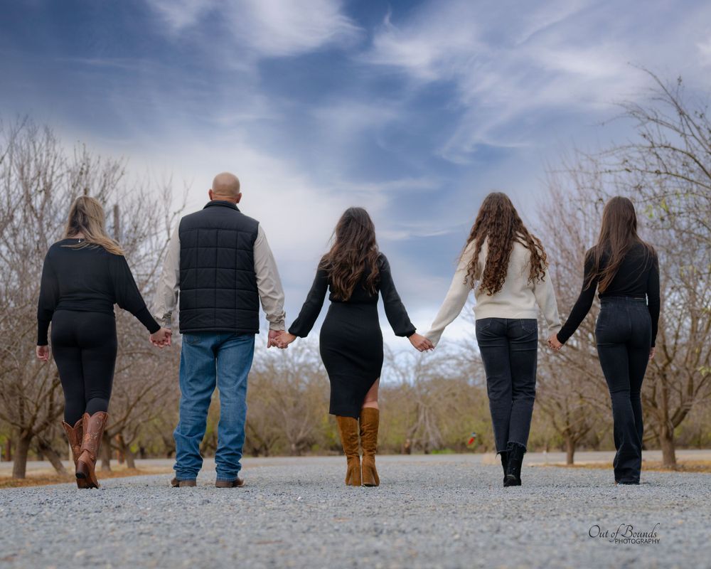 Family holding hands while walking together on gravel path during winter.