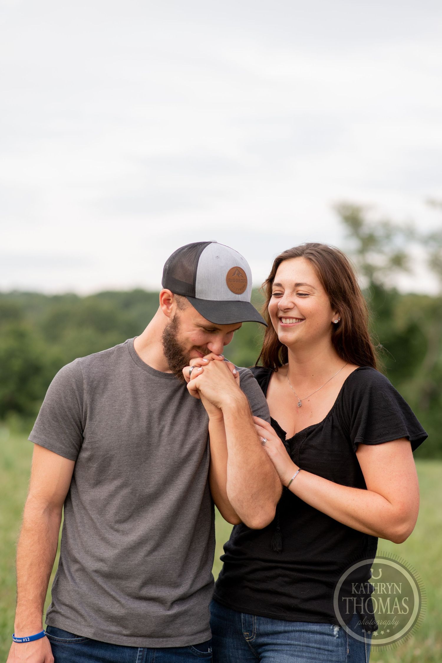 Loving couple shares a tender moment outdoors as one person kisses the other's hand.