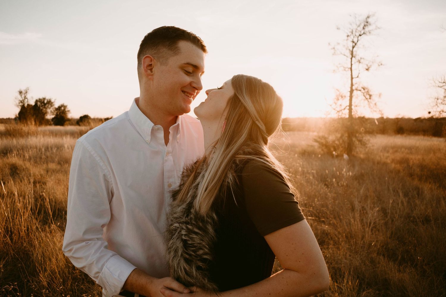 Couple sharing a romantic moment in a sunlit field wearing contrasting black and white.