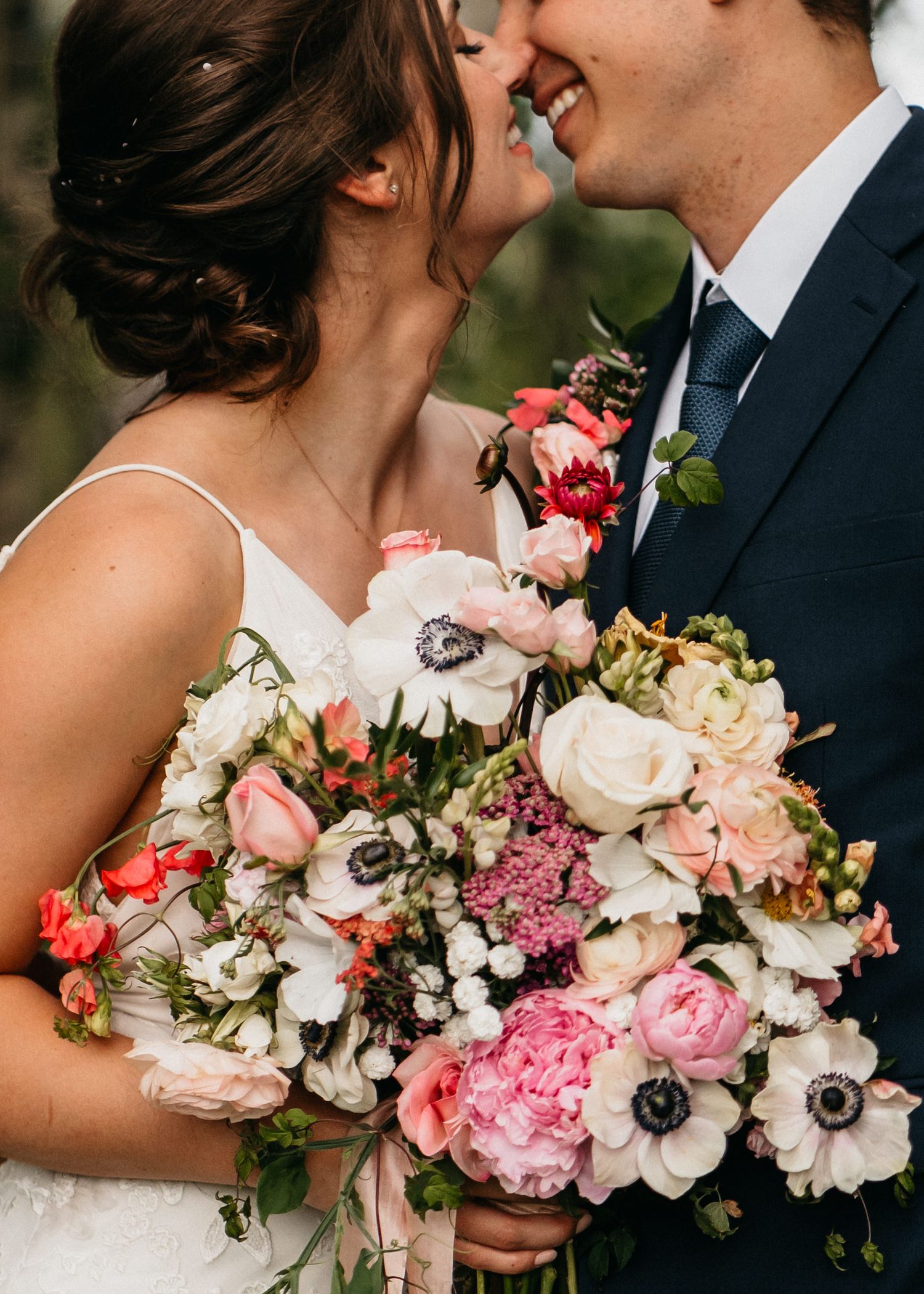 A Bride and groom share a kiss on their wedding day in Grande Prairie. A beautiful floral bouquet is being held by bride