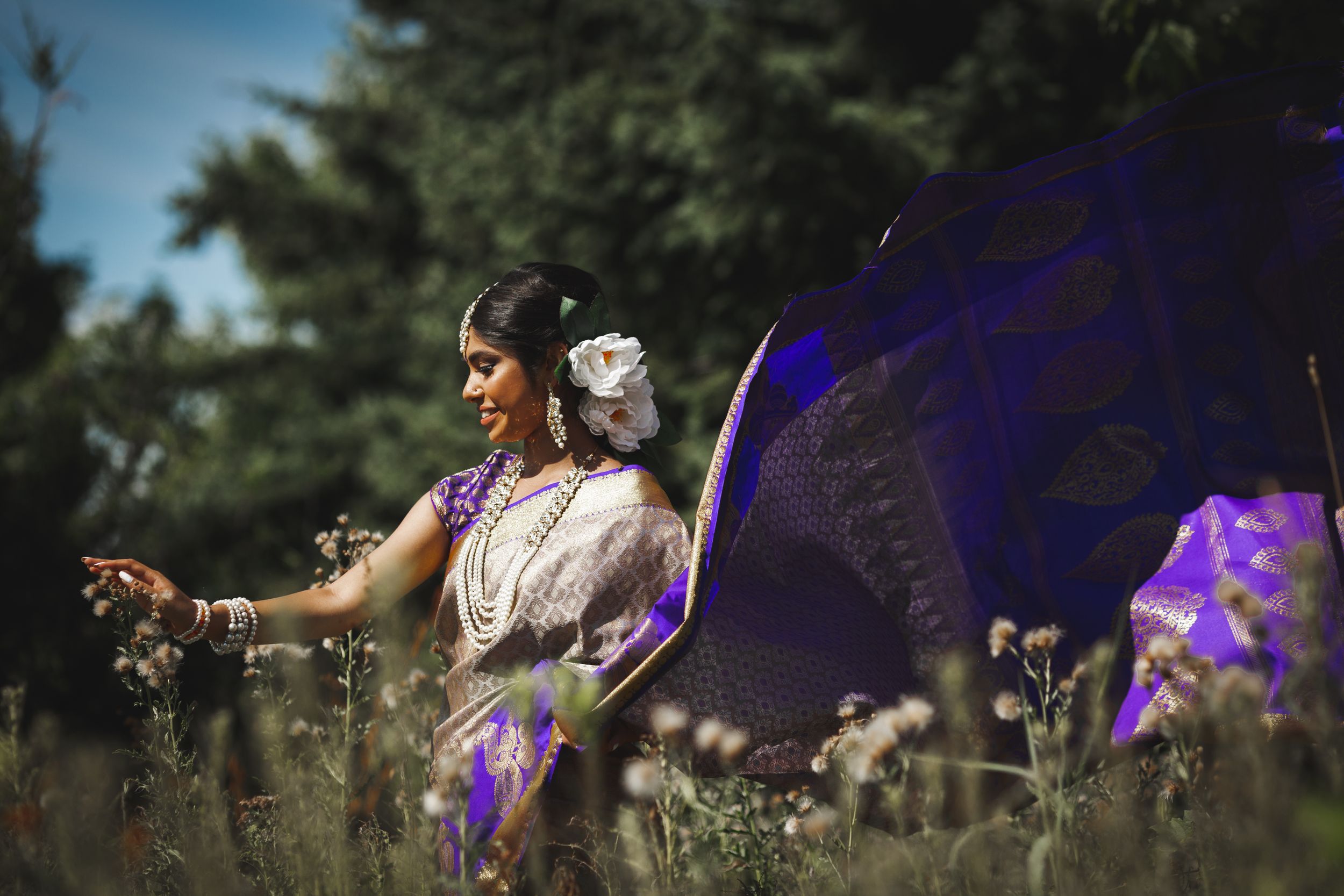 Outdoor photoshoot featuring purple lighting and natural foliage in the background.