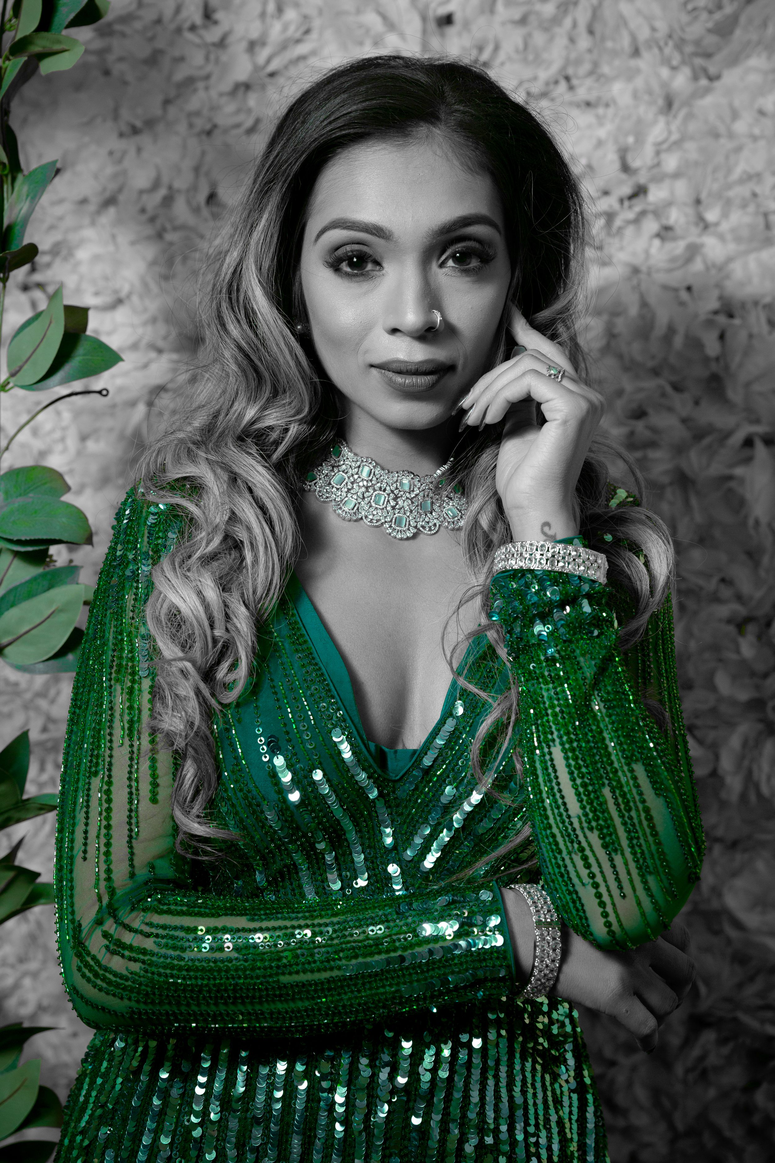 Fashion portraits in a sparkling emerald green sequin dress against a textured wall.