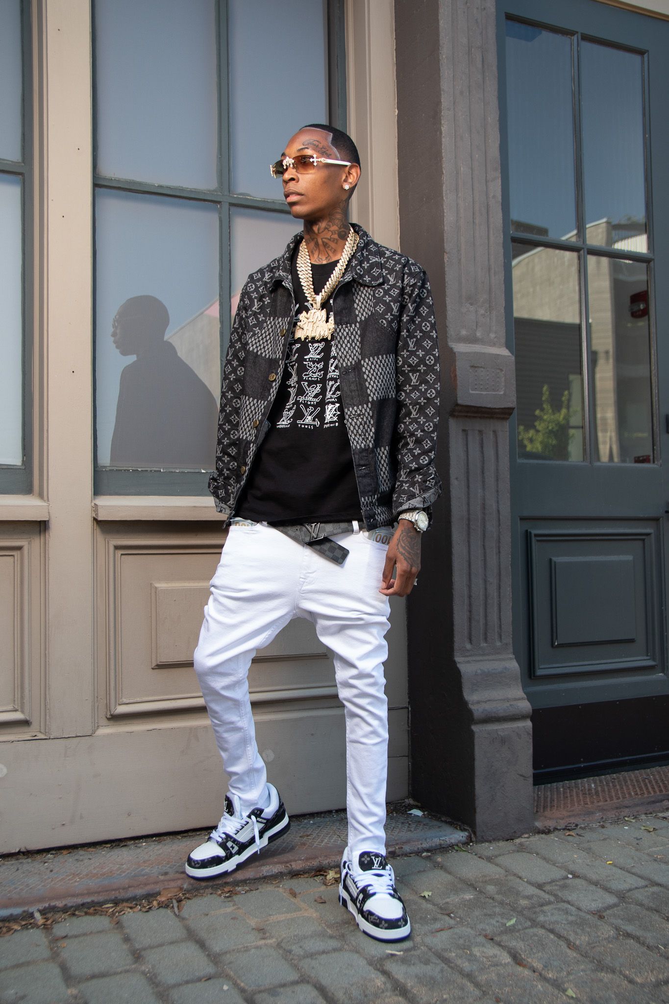 Street style fashion photo showing urban outfit with white pants, patterned jacket and sneakers.