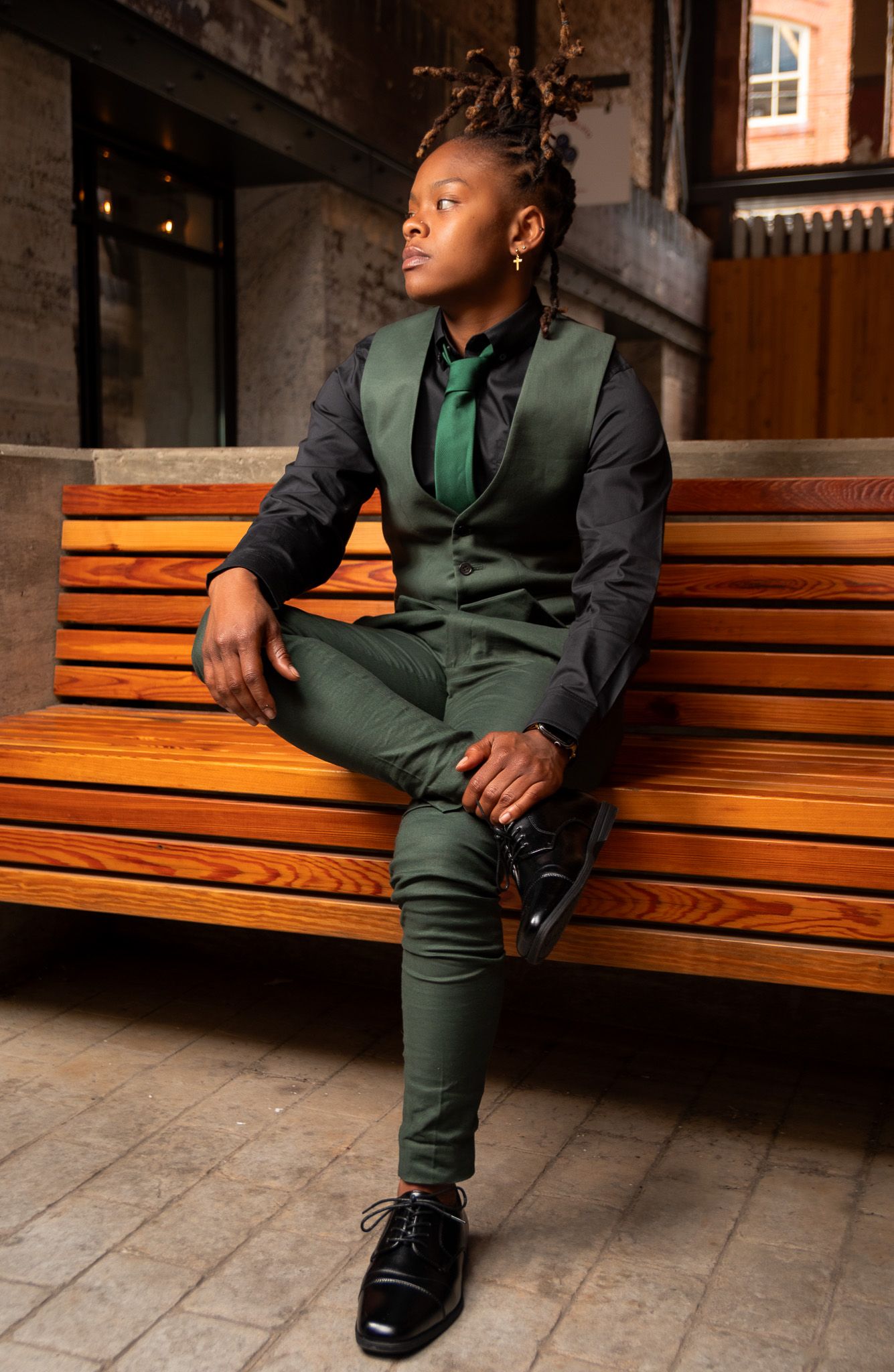 Dapper portrait of a subject sitting on a bench at the Mercantile on Morris.