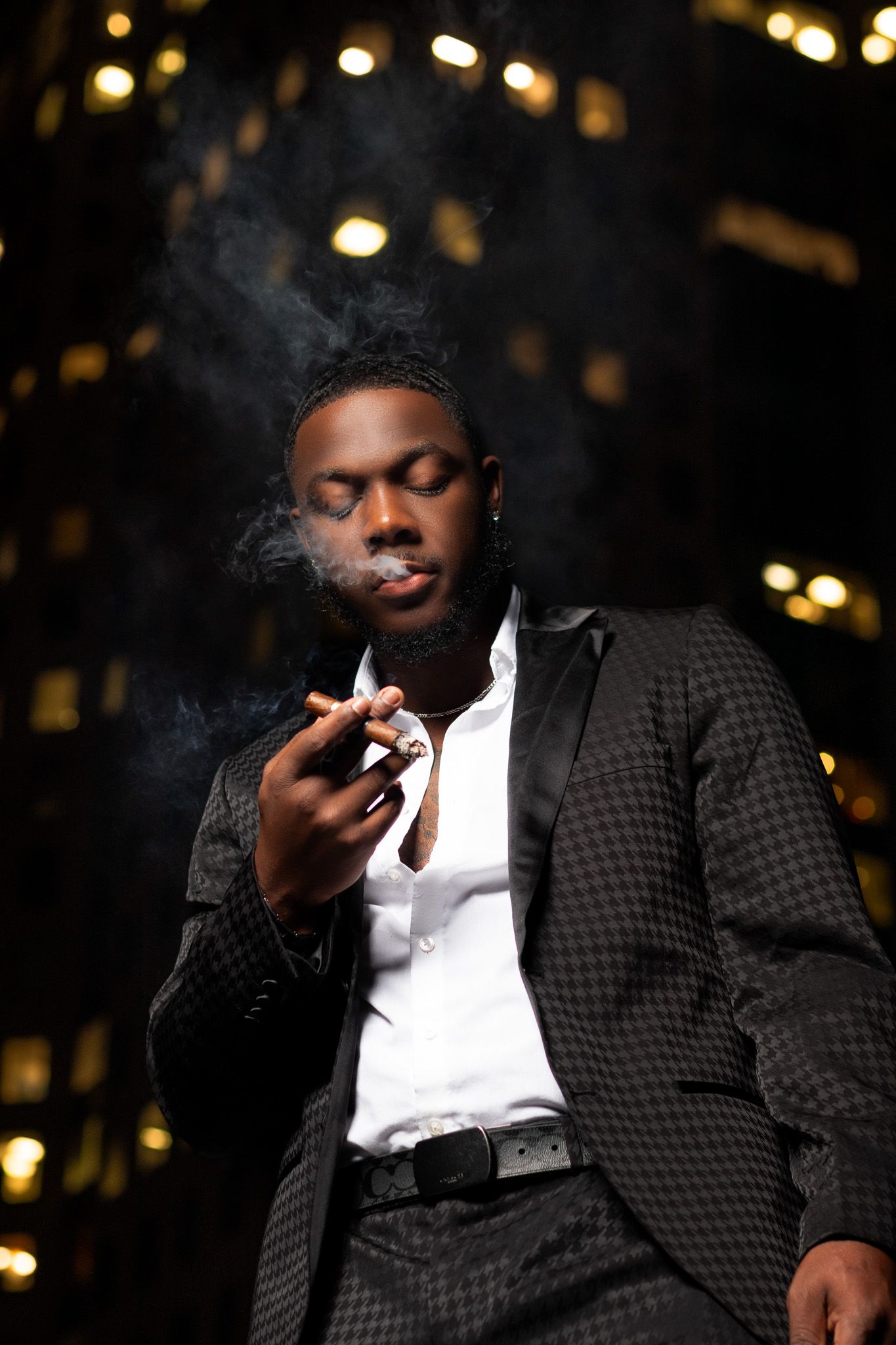 Dramatic night portrait with smoke and city lights showing urban fashion style.