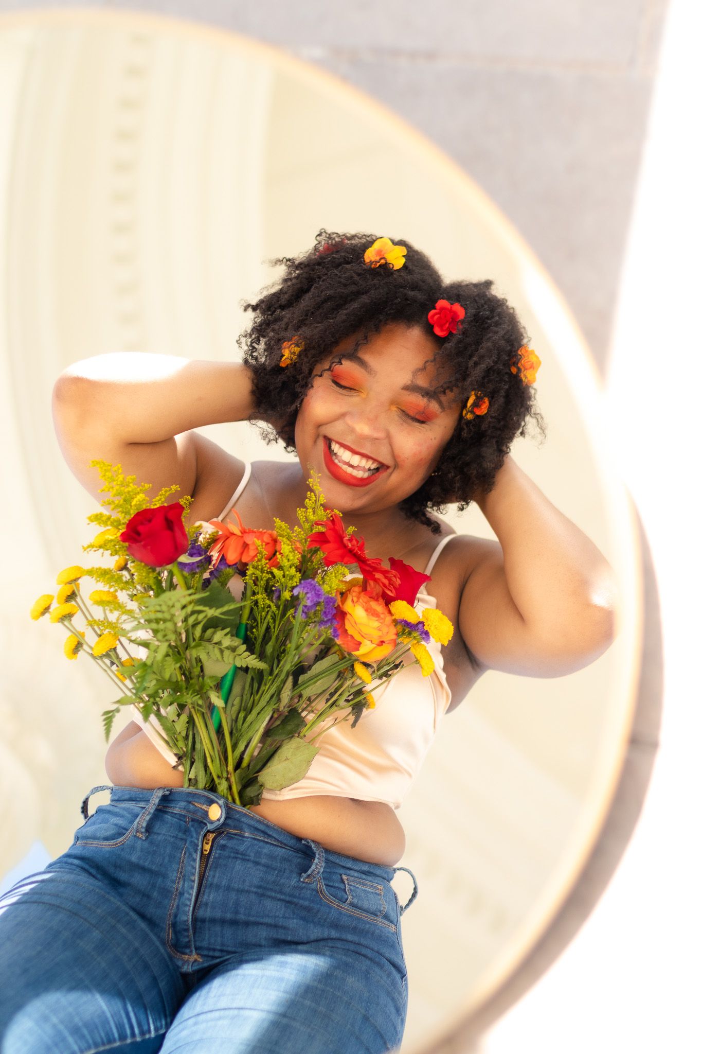 Joyful portrait with colorful flowers and natural lighting through circular window.