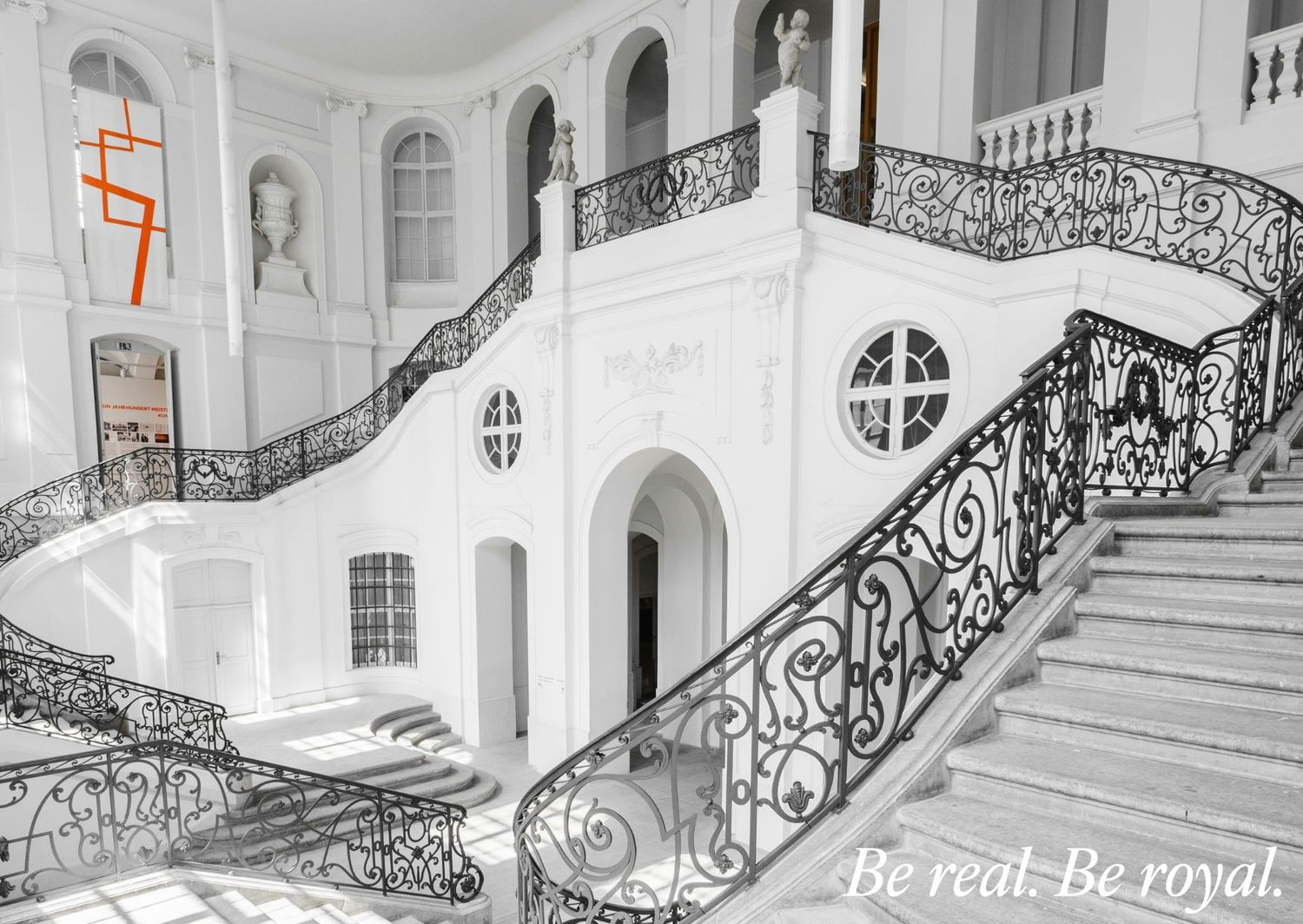 Grand staircase with ornate wrought iron railings in a classical white palace interior.