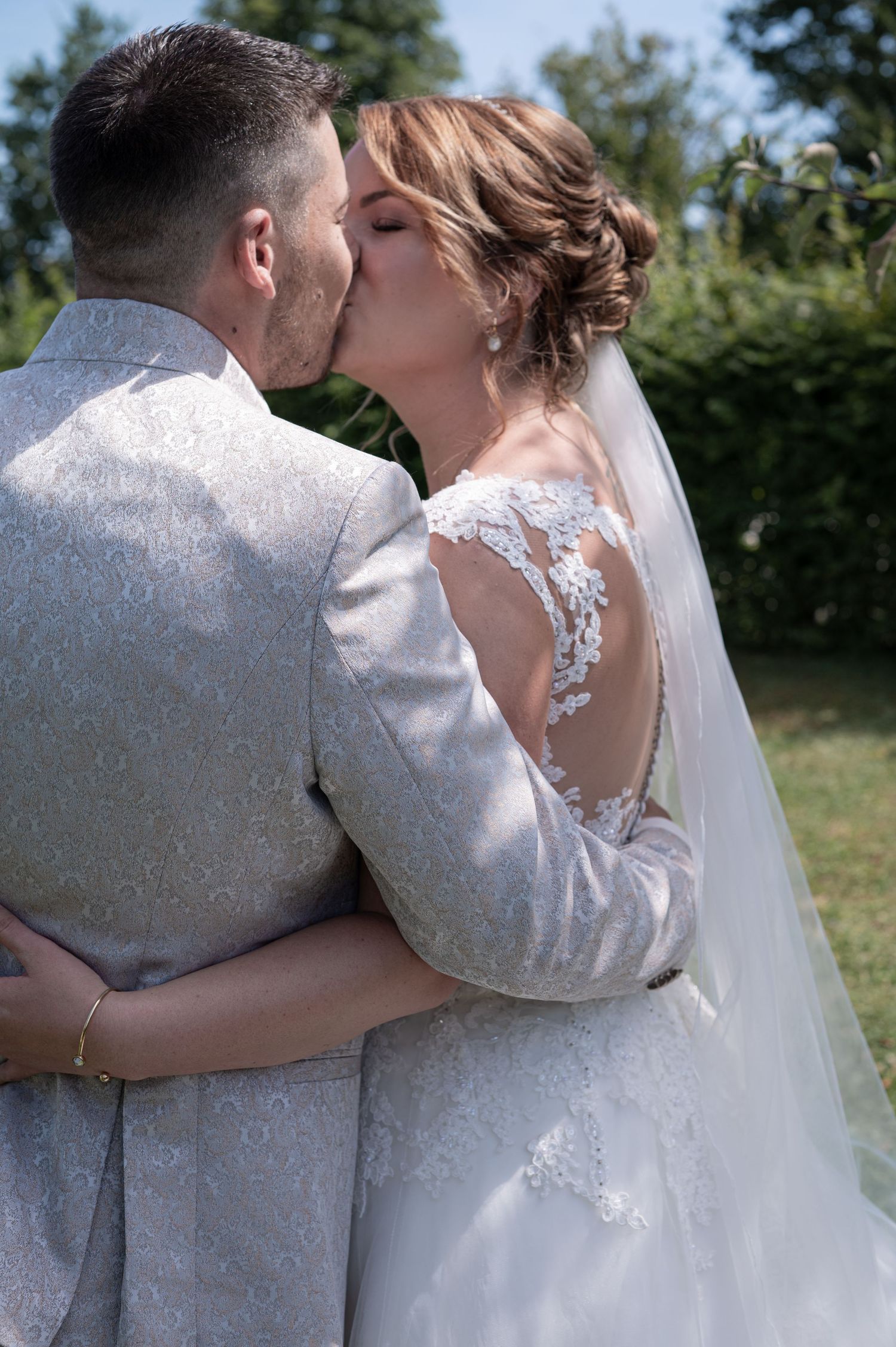 Frisch Vermählte geben sich an ihrem besonderen Tag einen romantischen Kuss im Freien in eleganter Hochzeitskleidung.