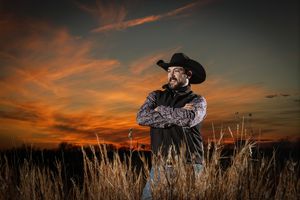 cowboy standing in a grassy field, dramatic sunset, off camera flash, photography, western photographer, cinch, marketing
