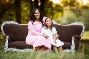 woman and daughter sitting on antique couch in a grassy field