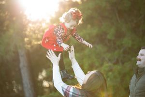 mom tossing baby girl up in the air with dad smiling in the background