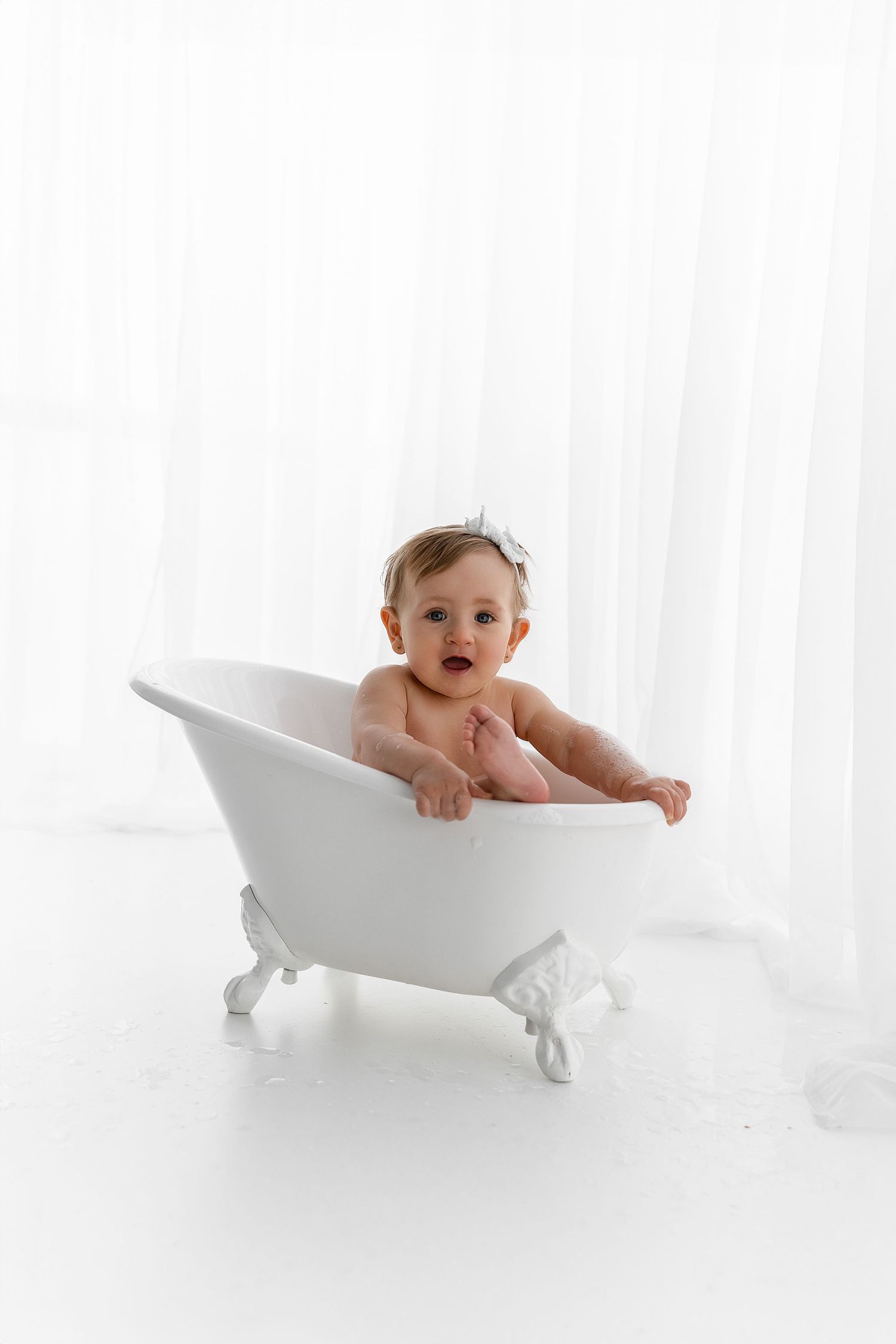 Baby sitting in a vintage-style white clawfoot bathtub.