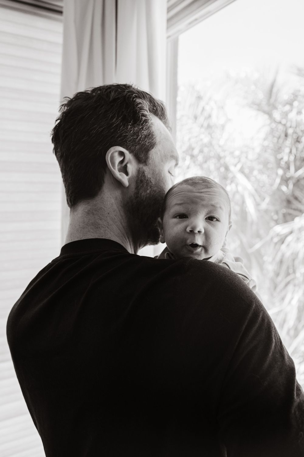 Tender black and white series showing intimate moments between parent and child on a sunny porch.