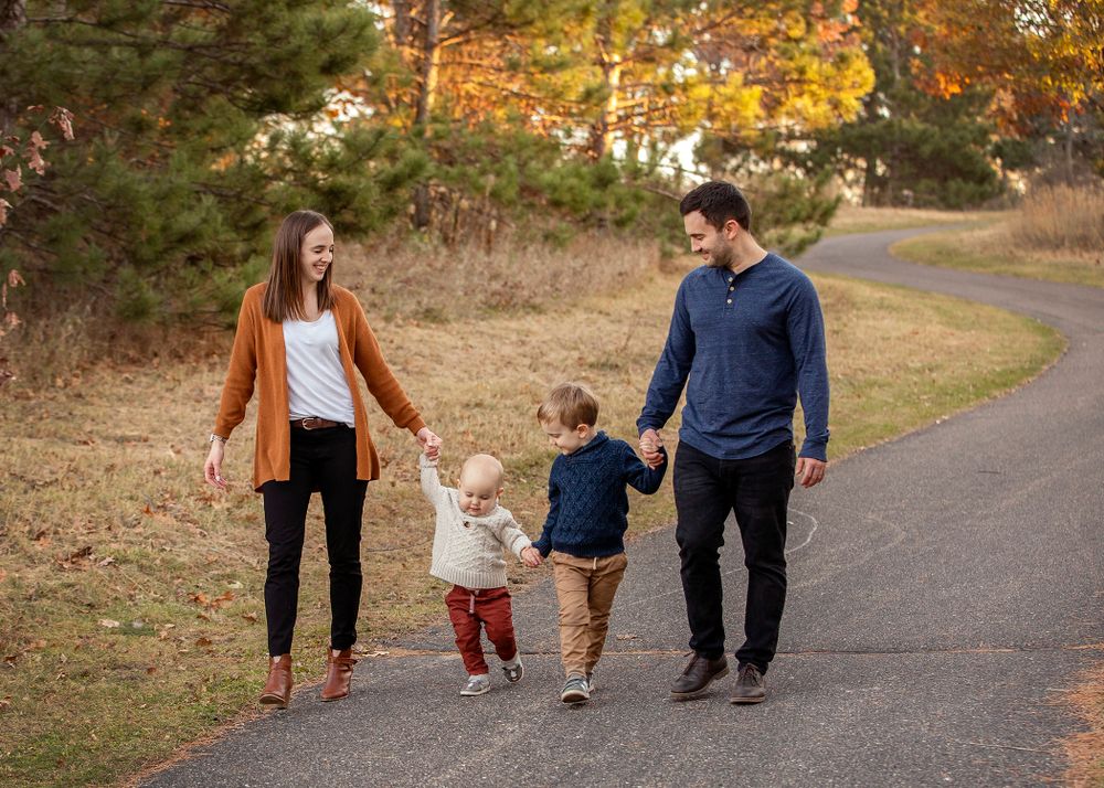 Family walking together hand in hand on a path during autumn season.