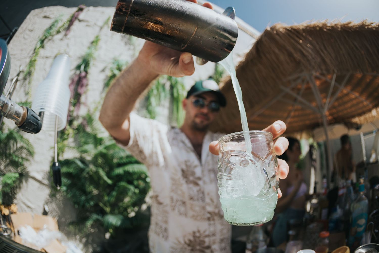 Someone pouring a fresh lime cocktail at an outdoor bar on a sunny day.