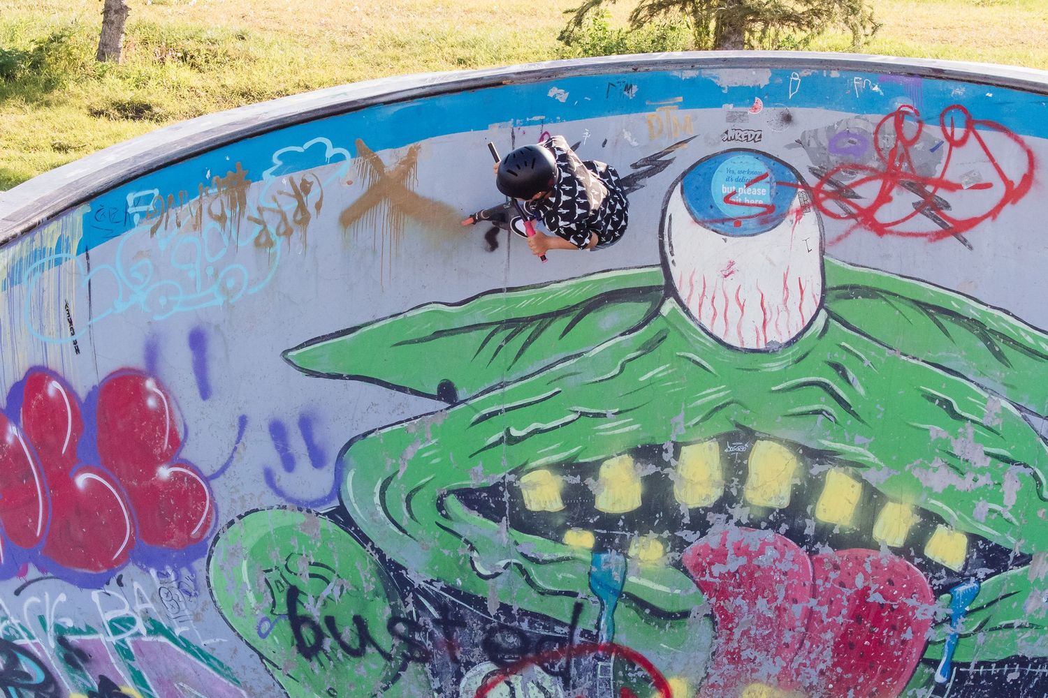 Colorful graffiti art featuring a monster face painted inside a skate park bowl.