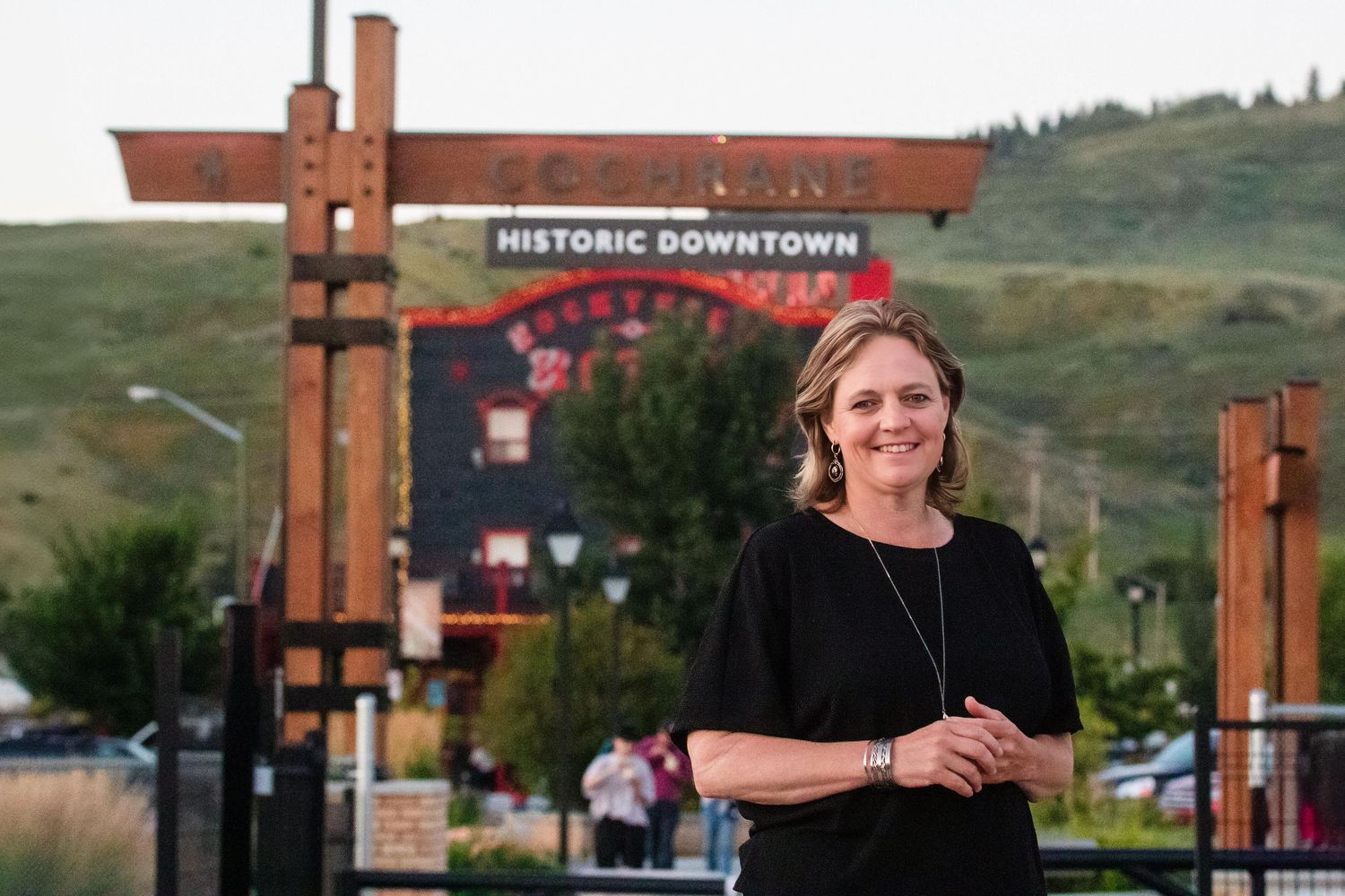 Woman smiling in front of a Historic Downtown sign with rolling hills in the background.