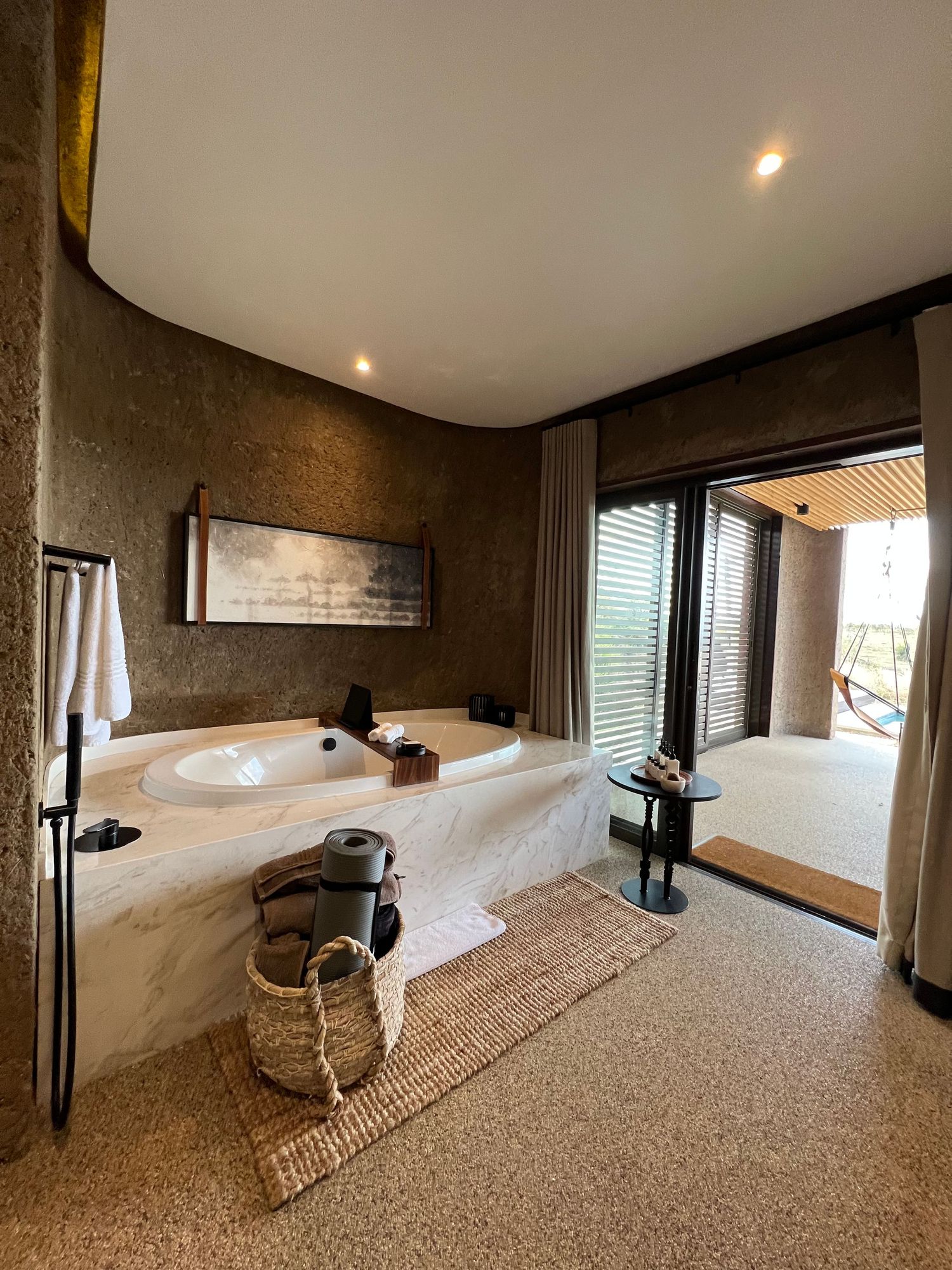 Elegant bathroom with freestanding soaking tub, natural textures and floor-to-ceiling windows.