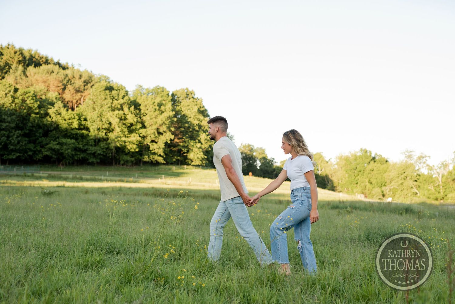 Couple walking hand in hand through sunny summer meadow.