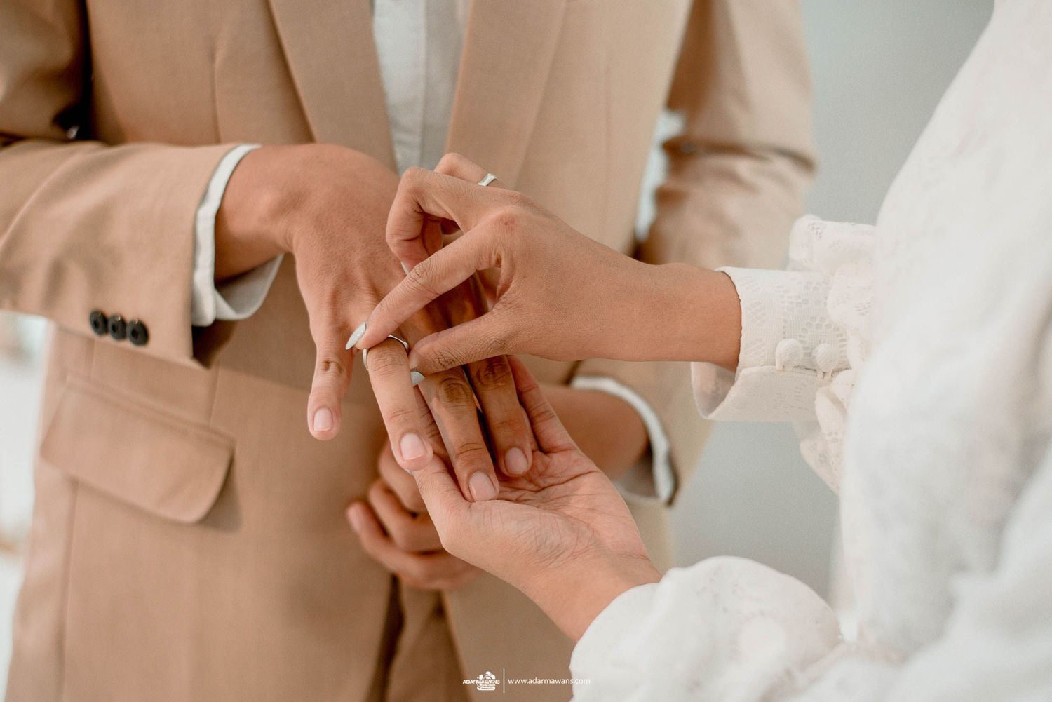 Close-up shot of hands during wedding ring exchange ceremony.